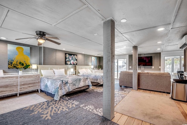 bedroom featuring multiple windows, decorative columns, wood finished floors, and a wall mounted air conditioner