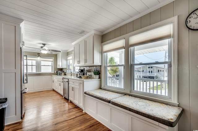 kitchen featuring stainless steel appliances, a wealth of natural light, light wood finished floors, and white cabinetry