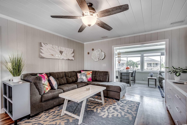 living room with visible vents, crown molding, a ceiling fan, and wood finished floors