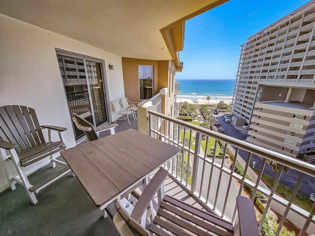 balcony with a water view, a view of the beach, and outdoor dining space