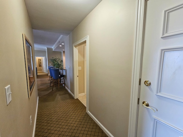 hallway featuring carpet and baseboards