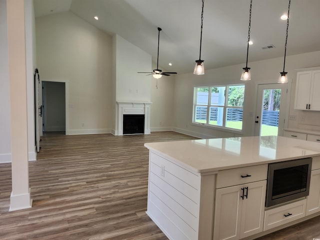 974 Crooked Oak Dr, Pawleys Island, SC 29585 - kitchen featuring stainless steel microwave, high vaulted ceiling, a ceiling fan, white cabinets, and decorative light fixtures