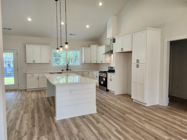 974 Crooked Oak Dr, Pawleys Island, SC 29585 - kitchen featuring stainless steel gas range oven, wall chimney range hood, light countertops, light wood-style flooring, and high vaulted ceiling