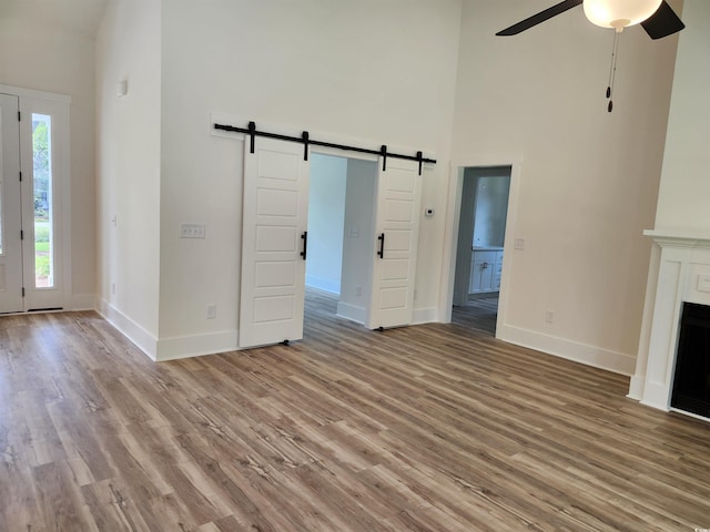 974 Crooked Oak Dr, Pawleys Island, SC 29585 - unfurnished living room featuring a barn door, a high ceiling, ceiling fan, and light wood finished floors