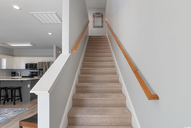 stairs with baseboards, recessed lighting, and wood finished floors
