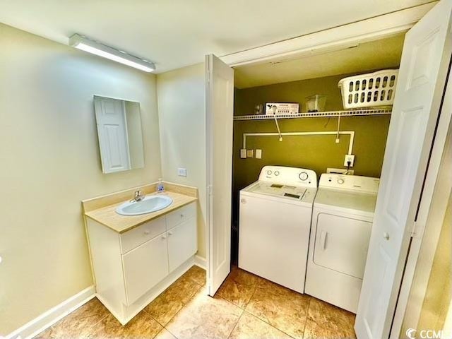clothes washing area with washing machine and clothes dryer, baseboards, a sink, and laundry area