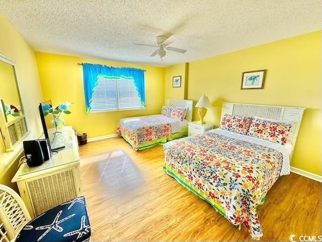 bedroom featuring baseboards, a ceiling fan, wood finished floors, and a textured ceiling