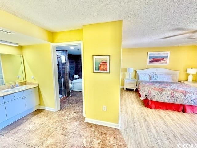 bedroom featuring baseboards, visible vents, a sink, and a textured ceiling