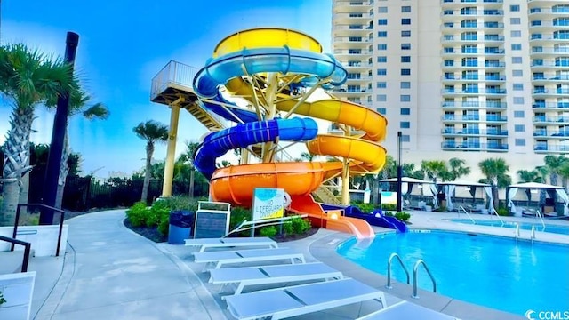 community pool with a water slide and a patio