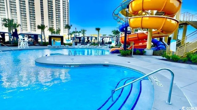 pool with a patio area and a water slide