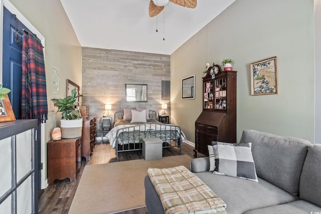 bedroom with wood walls, an accent wall, a high ceiling, and wood finished floors
