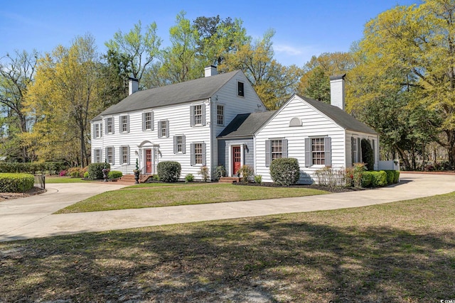 colonial inspired home featuring a front yard and a chimney