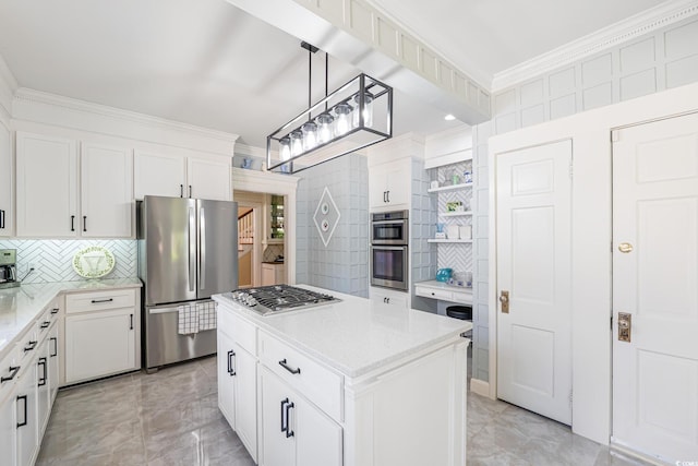 kitchen featuring white cabinets, backsplash, a kitchen island, crown molding, and appliances with stainless steel finishes