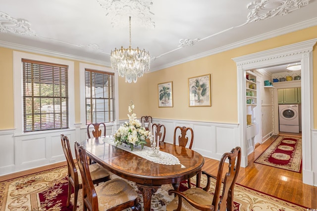 dining room featuring a chandelier, light wood-type flooring, crown molding, and washer / clothes dryer