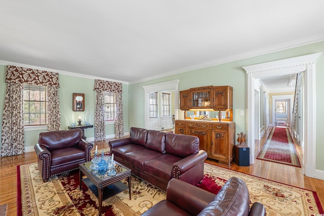 living area with light wood-type flooring, baseboards, and ornamental molding