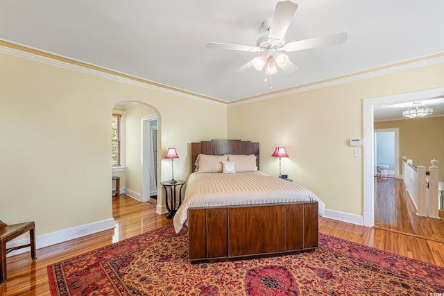 bedroom featuring baseboards, arched walkways, and light wood-style flooring