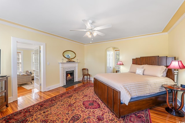 bedroom featuring a premium fireplace, wood finished floors, and crown molding