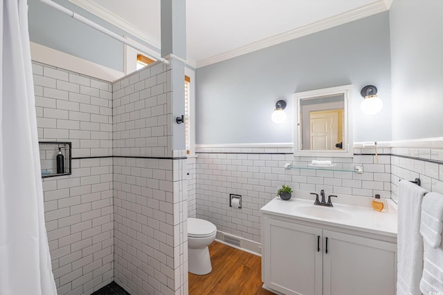 bathroom with a shower stall, crown molding, vanity, tile walls, and toilet