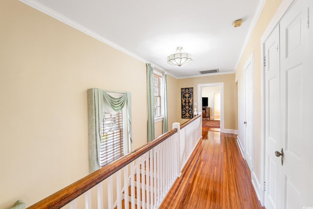 hallway with visible vents, baseboards, an upstairs landing, wood finished floors, and crown molding