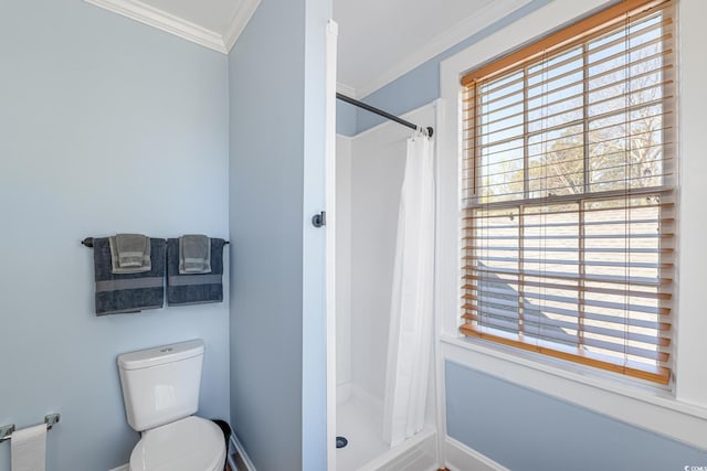 bathroom featuring toilet, baseboards, ornamental molding, and a stall shower