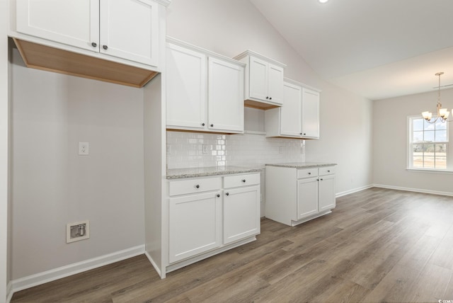 364 Hayloft Cir, Conway, SC 29526 - kitchen with lofted ceiling, decorative backsplash, white cabinets, wood finished floors, and a chandelier
