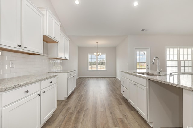 364 Hayloft Cir, Conway, SC 29526 - kitchen with a chandelier, light wood-type flooring, decorative backsplash, white cabinetry, and light stone countertops