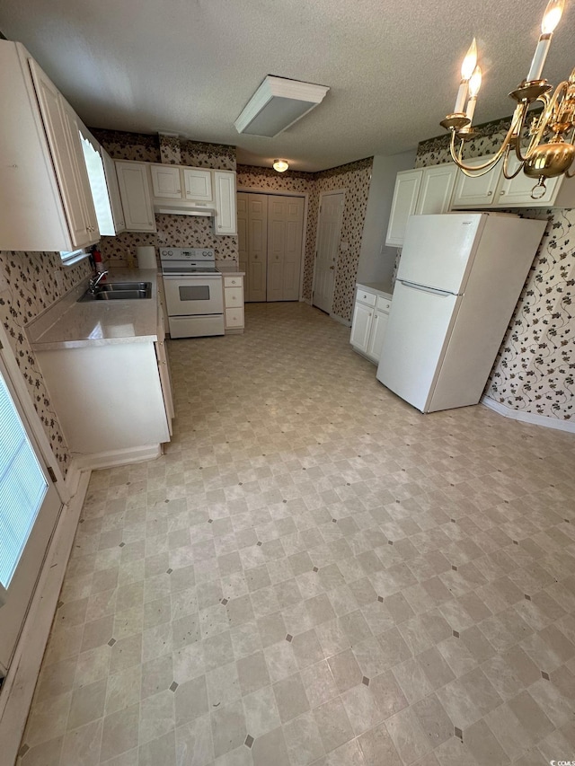 kitchen with a sink, white appliances, an inviting chandelier, white cabinetry, and under cabinet range hood