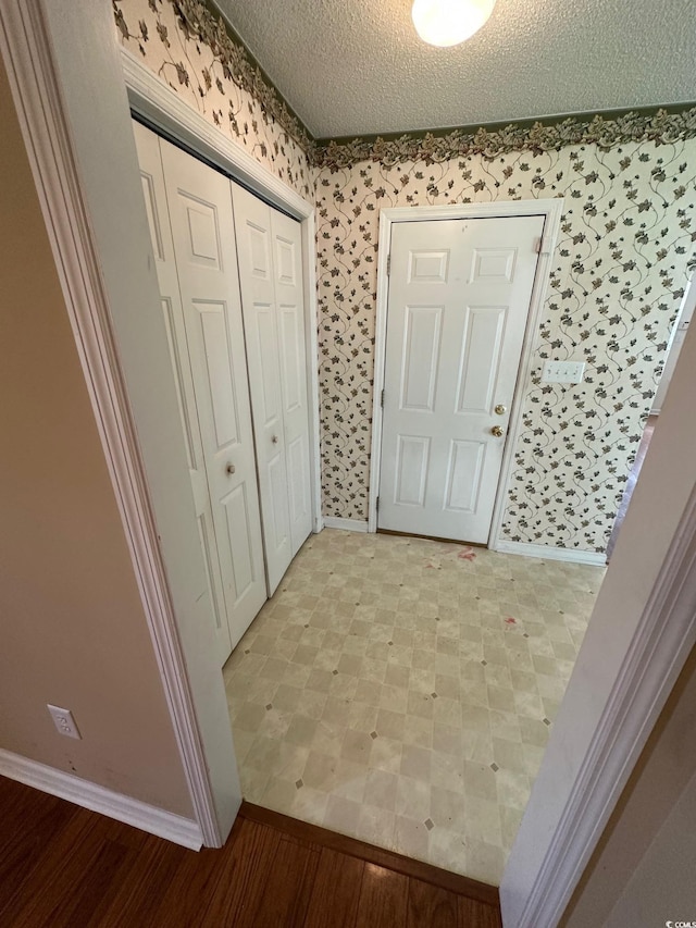 interior space with wallpapered walls, baseboards, and a textured ceiling