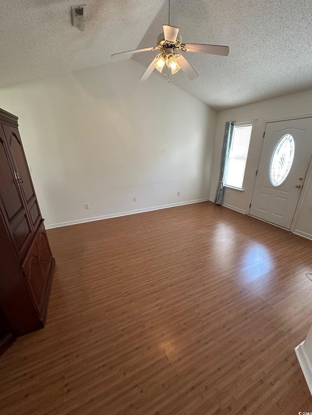 foyer featuring lofted ceiling, dark wood-style flooring, baseboards, a textured ceiling, and ceiling fan