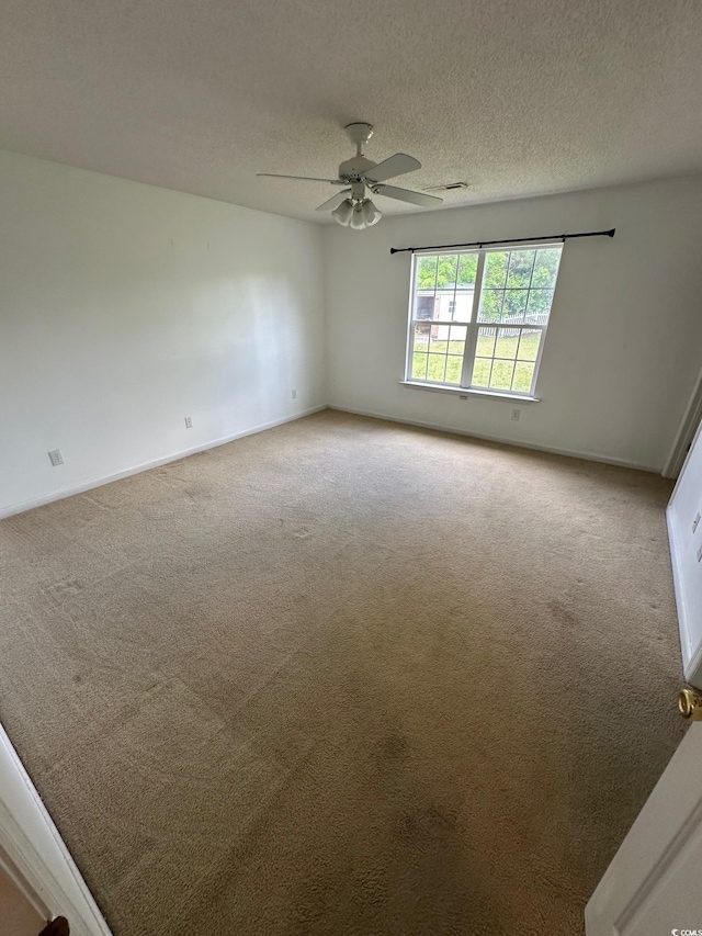 carpeted spare room featuring a textured ceiling, a ceiling fan, baseboards, and visible vents
