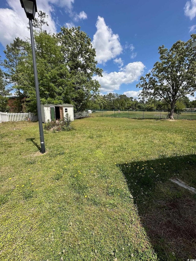 view of yard with a storage unit, an outbuilding, and fence