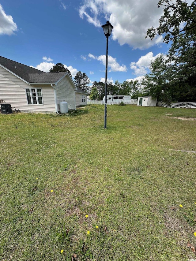 view of yard with central AC, an outbuilding, and a storage shed