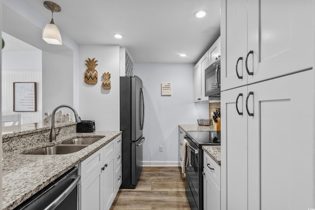 5508 Porcher Dr Unit 3, Myrtle Beach, SC 29577 - kitchen with black appliances, a sink, light wood-type flooring, white cabinets, and light stone countertops