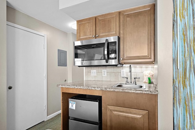 kitchen featuring light stone countertops, a sink, stainless steel appliances, and decorative backsplash