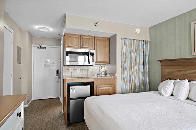 bedroom featuring freestanding refrigerator, baseboards, dark carpet, and a sink