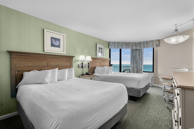 bedroom featuring a water view, dark carpet, and baseboards