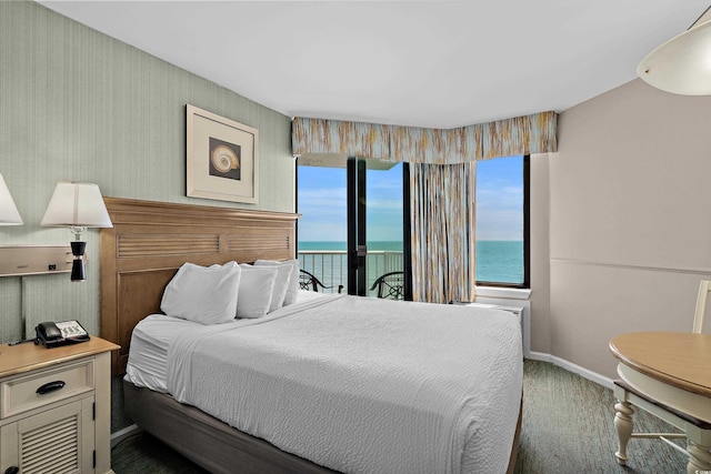 bedroom with baseboards, access to outside, a water view, and carpet