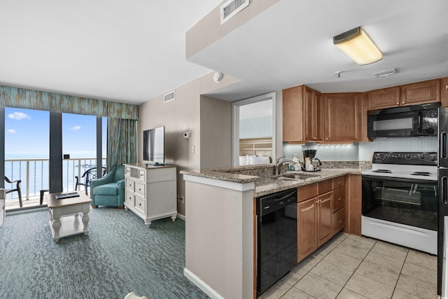 kitchen featuring visible vents, black appliances, light stone countertops, and a sink