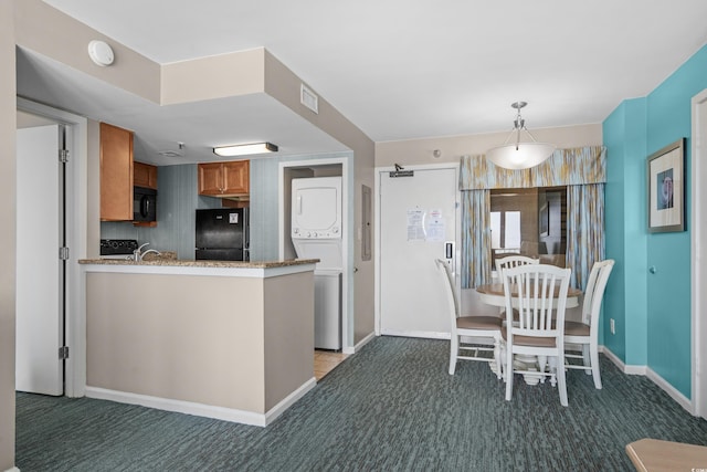 kitchen with stacked washer / dryer, black appliances, and carpet floors