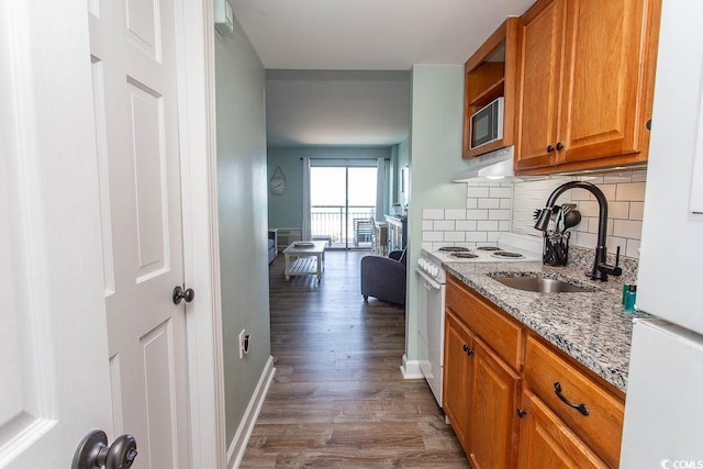 2001 S Ocean Blvd Unit 207, Myrtle Beach, SC 29577 - kitchen with white appliances, dark wood-style floors, brown cabinets, light stone counters, and backsplash