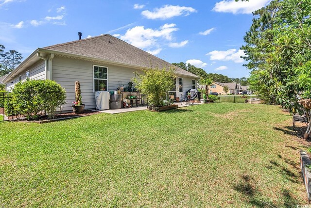 522 Heartland Ct, Murrells Inlet, SC 29576 - back of property featuring a shingled roof, fence, a patio, and a lawn