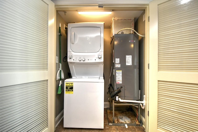 laundry room with laundry area, heating unit, and stacked washer / drying machine