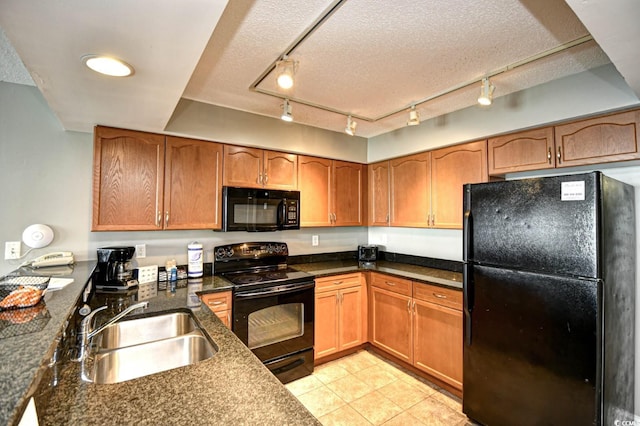 kitchen with light tile patterned floors, a textured ceiling, black appliances, brown cabinetry, and a sink