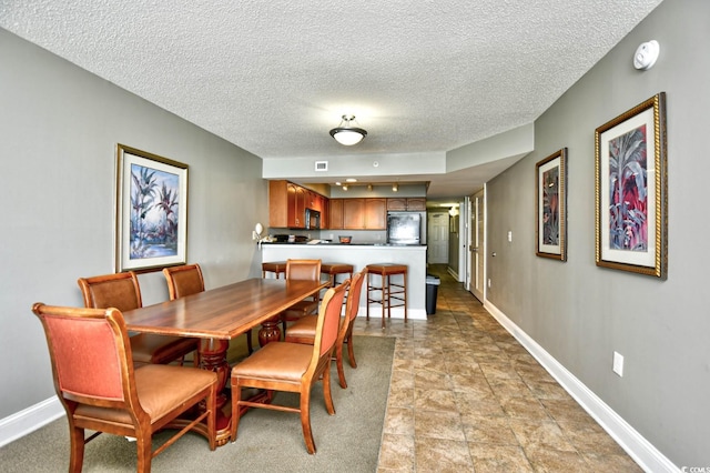 dining space featuring a textured ceiling, baseboards, and visible vents