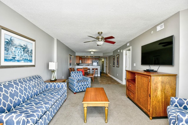 carpeted living area featuring a textured ceiling, baseboards, a ceiling fan, and visible vents