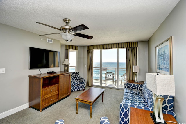carpeted living room featuring a textured ceiling, baseboards, a ceiling fan, and visible vents