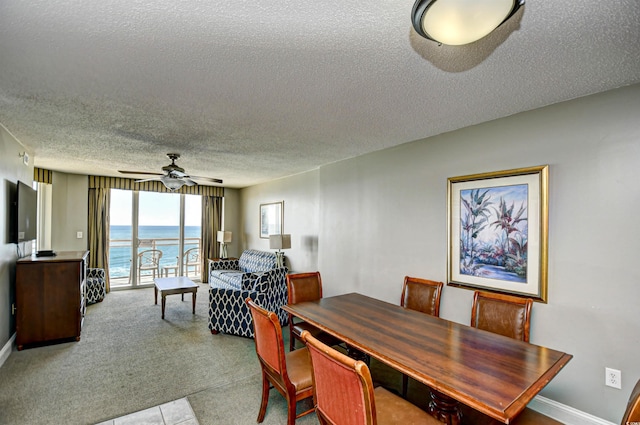 dining room with a water view, ceiling fan, baseboards, and a textured ceiling