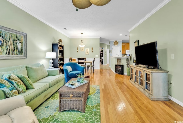 living room featuring ornamental molding, light wood finished floors, baseboards, and recessed lighting