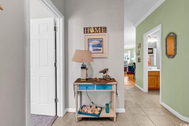 corridor with light tile patterned floors, baseboards, and a sink