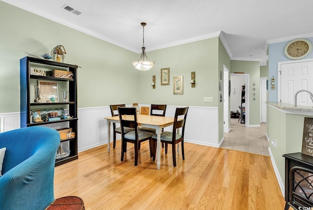 dining space with ornamental molding, wainscoting, and light wood finished floors